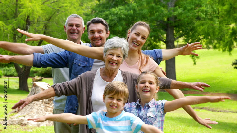 Multi generation family posing and smiling at camera in a park Multi generation family posing and smiling at camera in a park