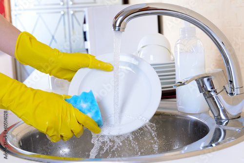 Close up hands of woman washing dishes in kitchen