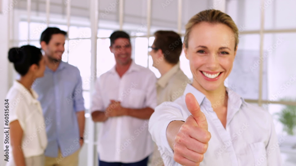Attractive blonde businesswoman showing thumbs up to camera Attractive blonde businesswoman showing thumbs up to camera