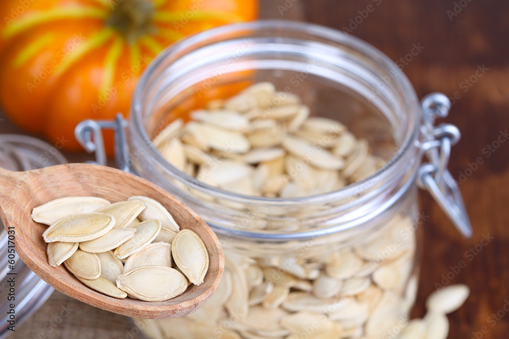 Pumpkin seeds in spoon and jar on table close up Pumpkin seeds in spoon and jar on table close up