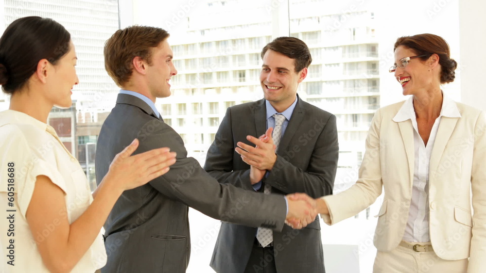 Business people shaking hands at interview while others applaud Business people shaking hands at interview while others applaud