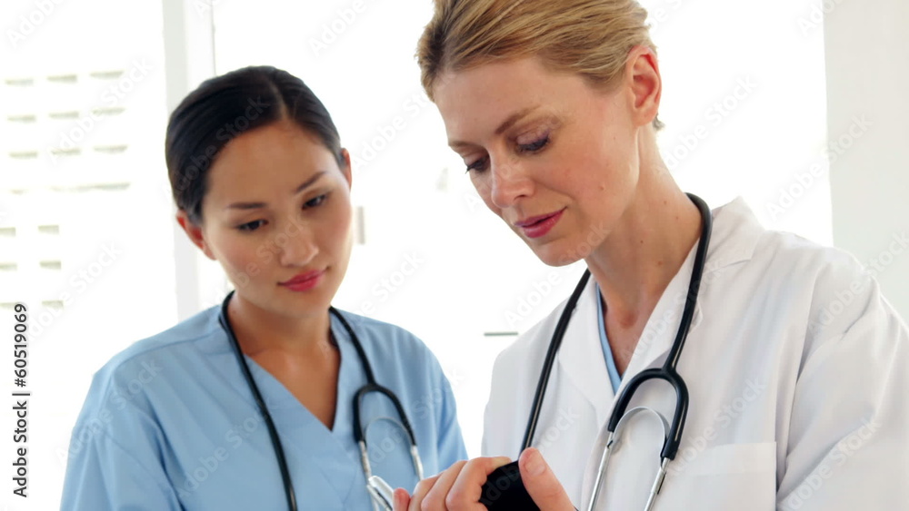 Two doctors looking over a file and smiling at camera Two doctors looking over a file and smiling at camera