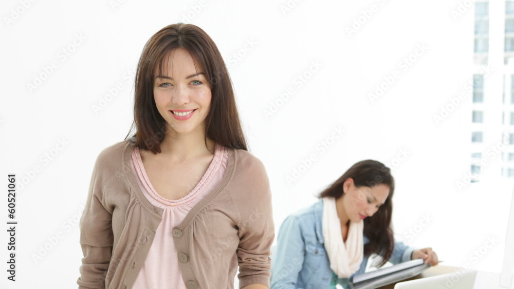 Creative businesswoman smiling at camera with colleague Creative businesswoman smiling at camera with colleague