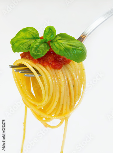 Spaghetti na widelcu z bazylią i sosem na białym tle.