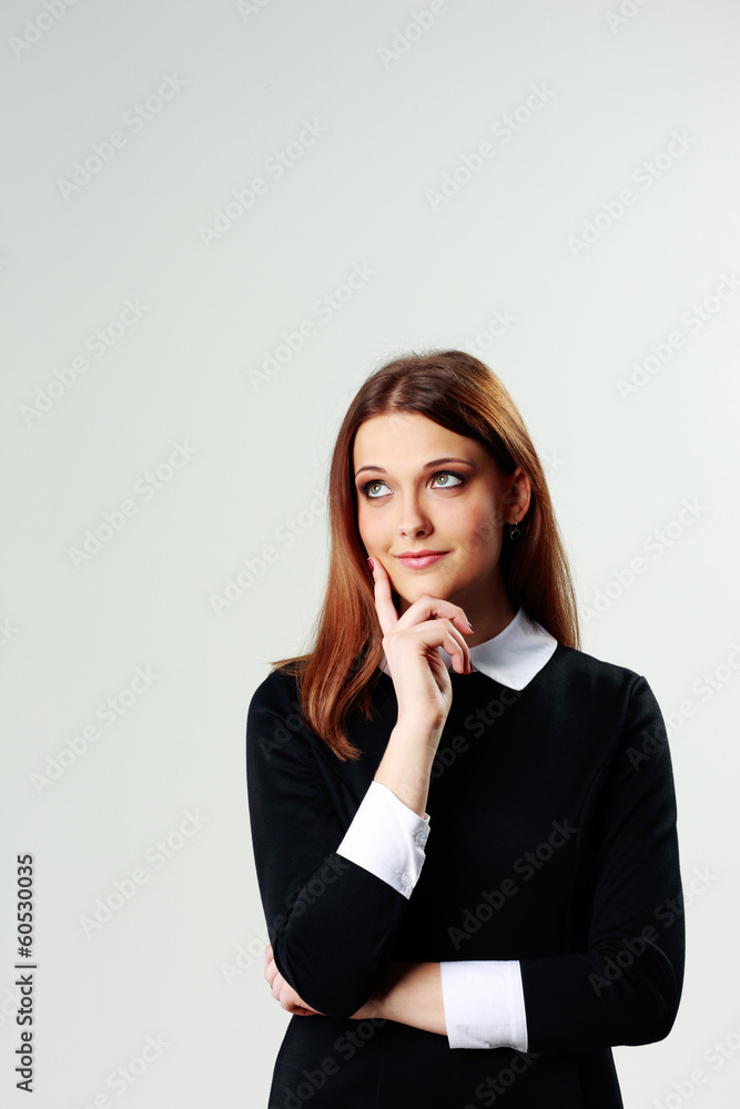 Young thoughtful woman looking up on gray background Young thoughtful woman looking up on gray background
