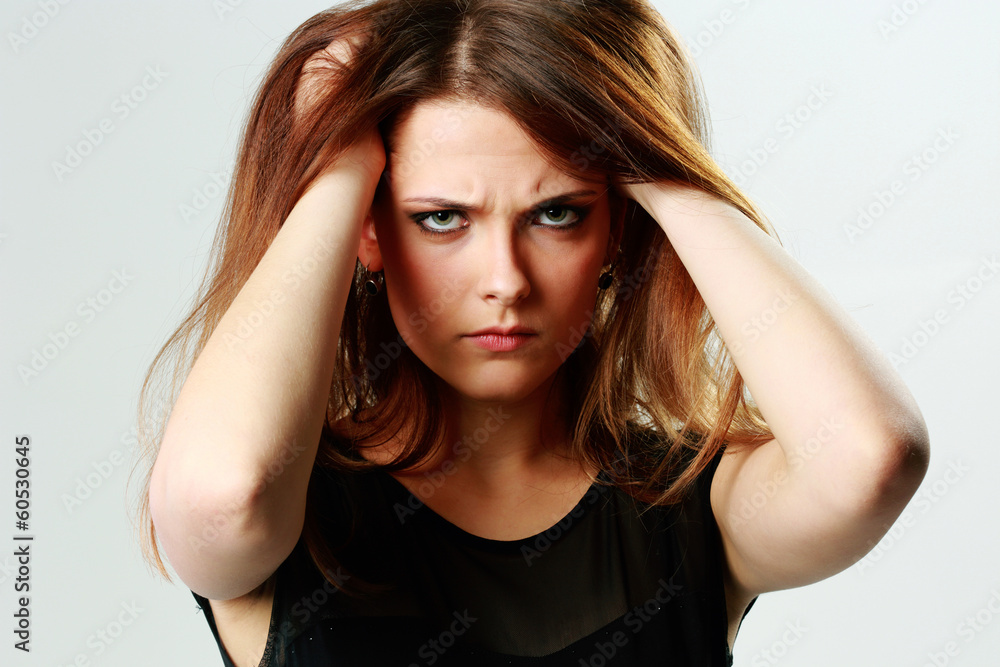 Young angry woman touching her head on gray background Young angry woman touching her head on gray background
