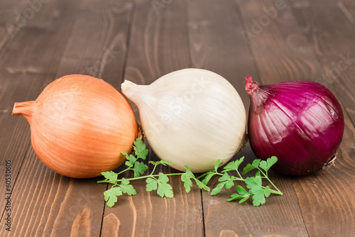 Yellow, withe and red onion on a wooden background