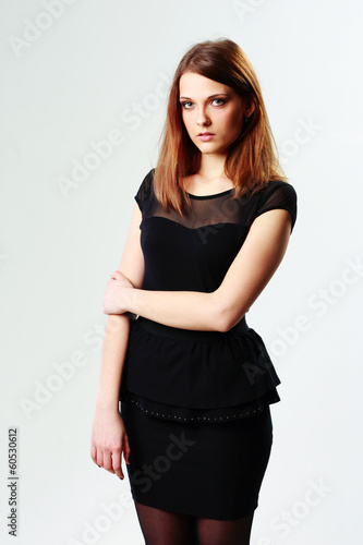 Young pensive woman standing on gray background