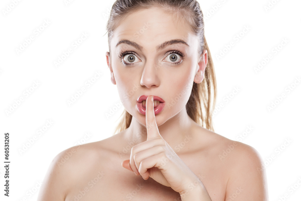 beautiful girl holds a finger to her mouth