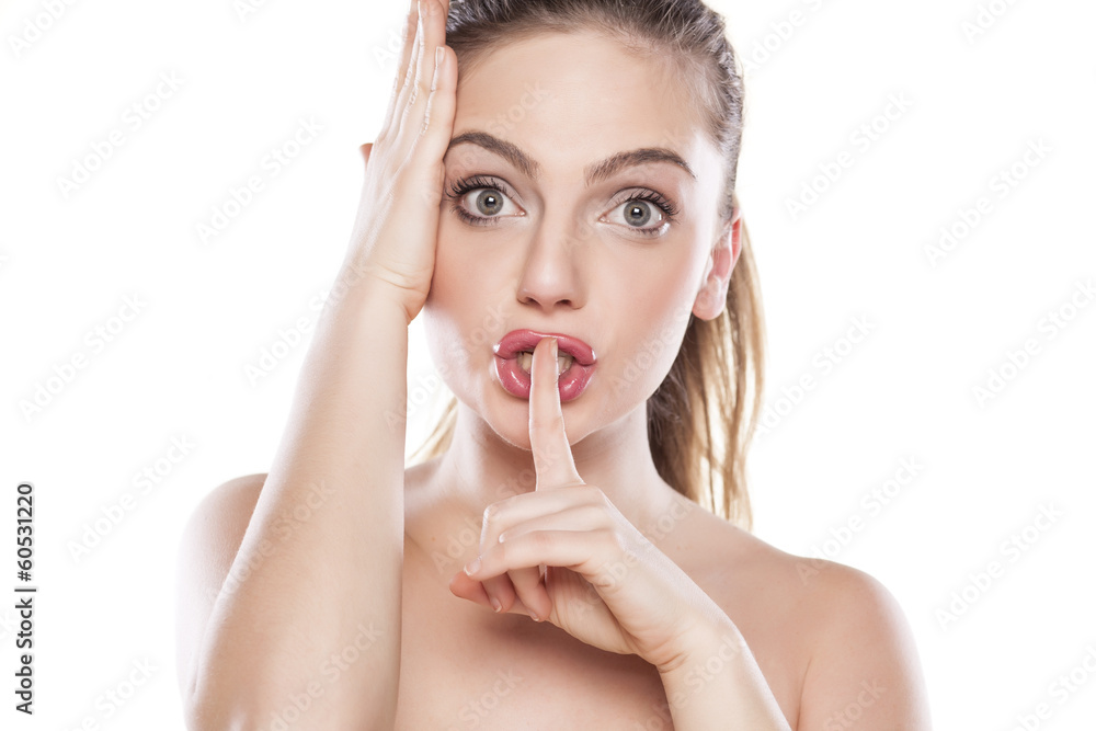 beautiful girl holds a finger to her mouth