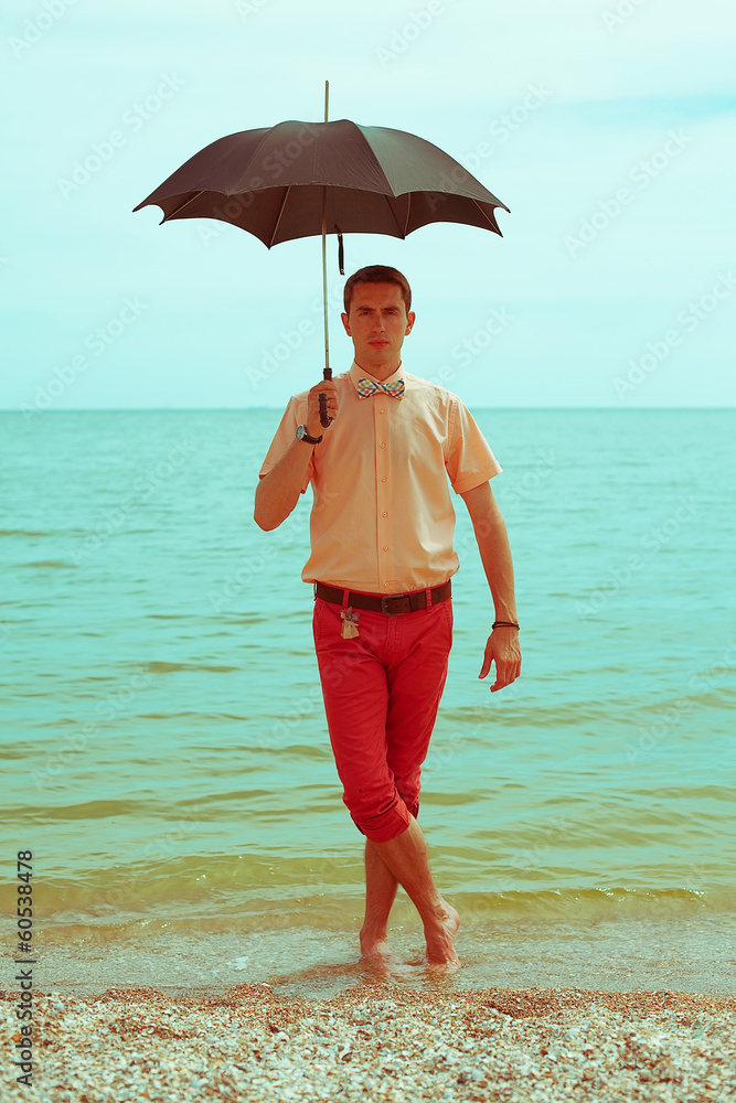 Summer vacation concept: handsome hipster with umbrella
