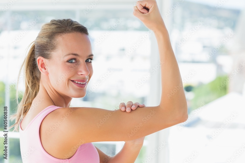 Young woman flexing muscles in gym