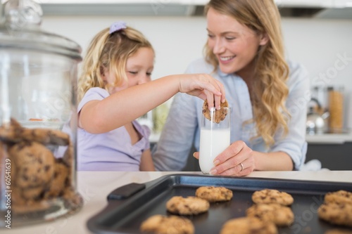 Quadro em tela Woman with daughter dipping cookie in milk