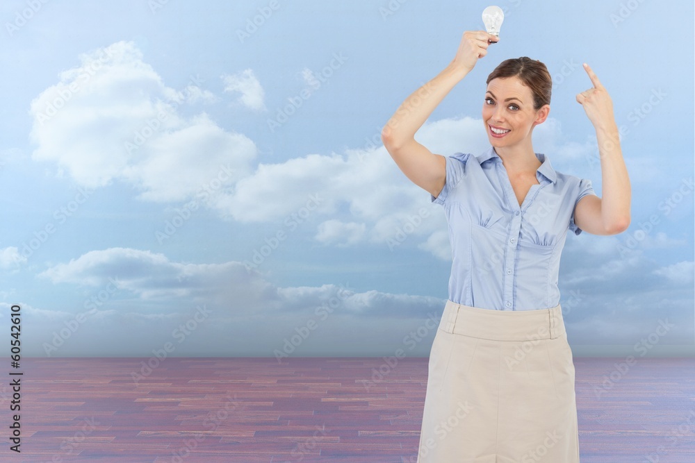 Composite image of classy businesswoman holding light bulb above Composite image of classy businesswoman holding light bulb above