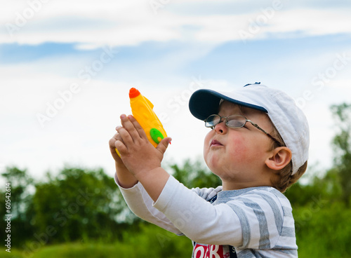 Little boy plays with a water pistol