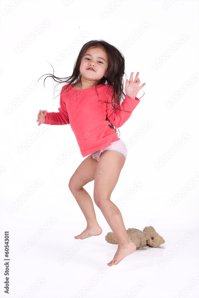 petite fille en culotte au réveil avec son ours en peluche Stock
