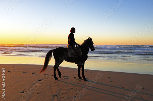 Horse riding on the beach at sunset