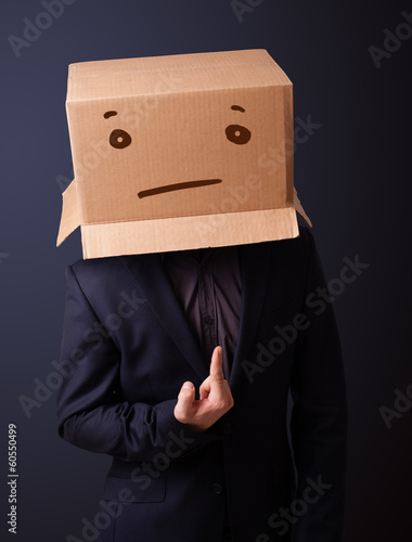 Young man gesturing with a cardboard box on his head with straig