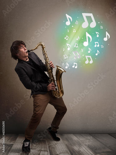 Young musician playing on saxophone while musical notes explodin photo