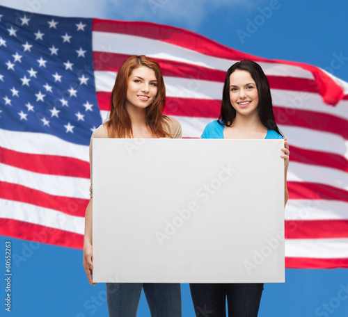 two smiling young girls with blank white board