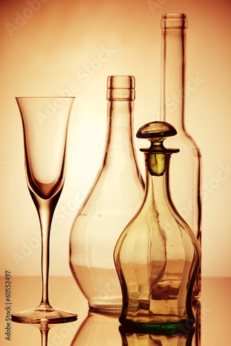 Four empty transparent wine glasses and bottles composition