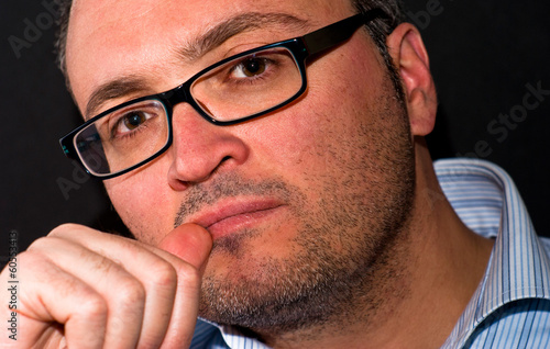 Pensive bearded caucasian man wearing eyeglasss photo