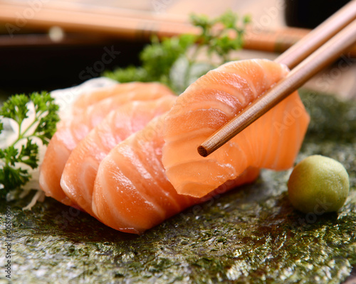Chopsticks holding salmon sashimi slice