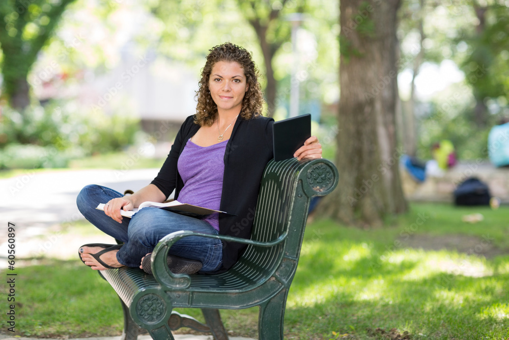 Confident Student Sitting On Bench At Campus Confident Student Sitting On Bench At Campus