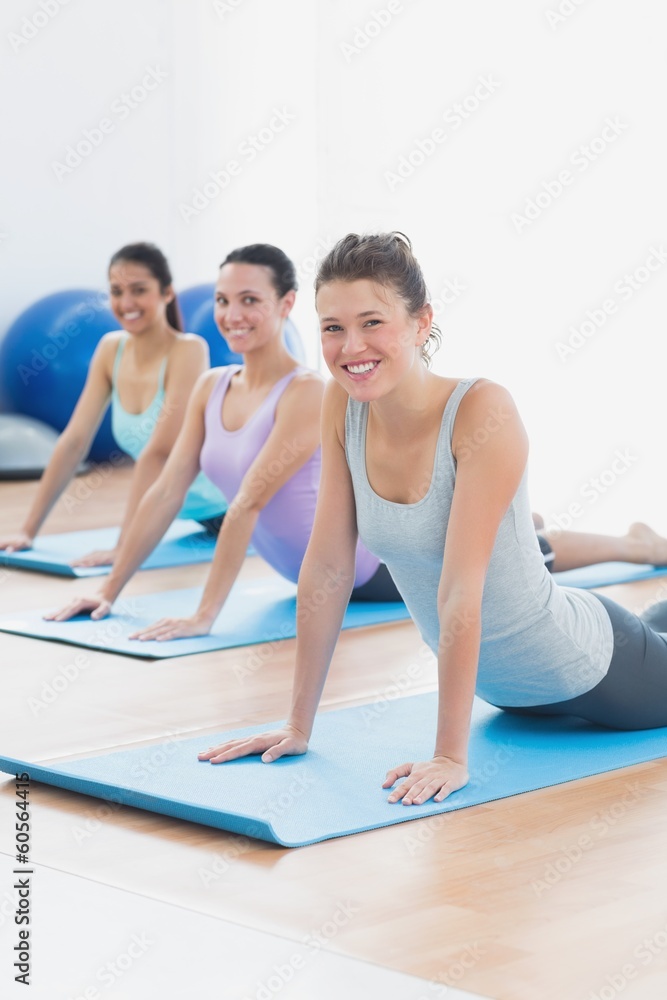 Smiling class doing the cobra pose in fitness studio
