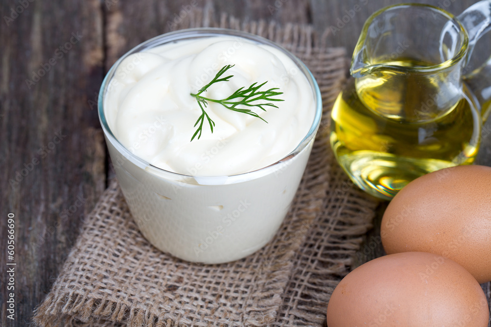 Mayonnaise in bowl with egg and olive oil on an old wooden table Mayonnaise in bowl with egg and olive oil on an old wooden table