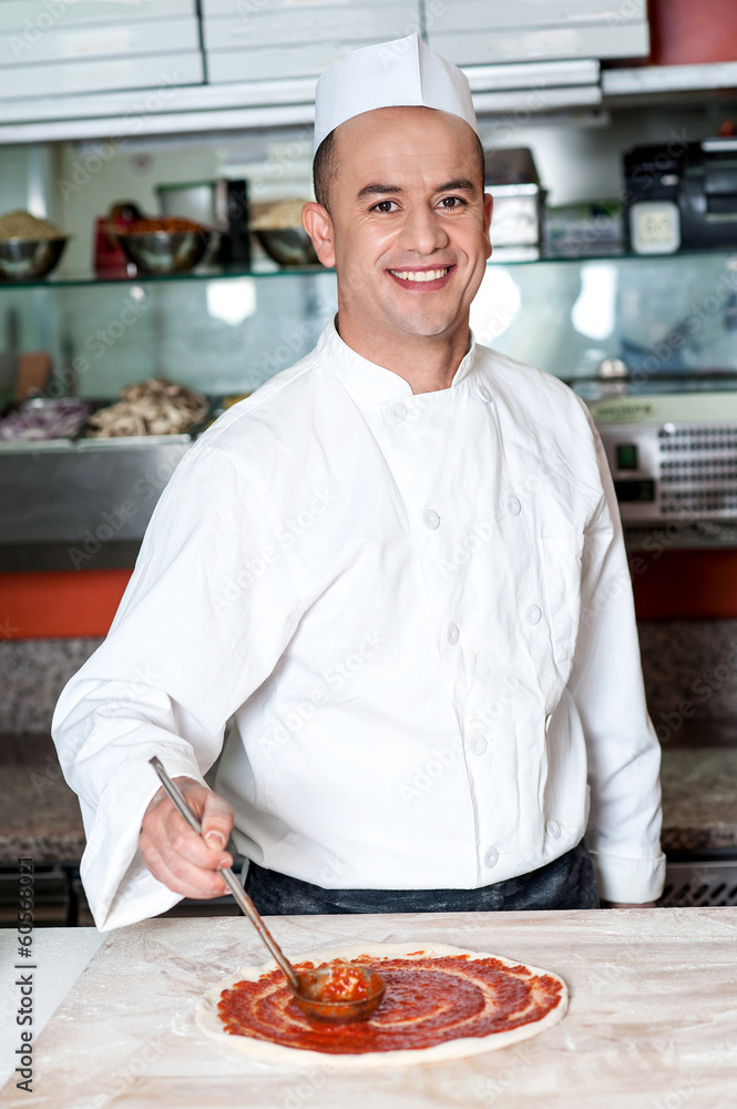 Smiling chef making pizza