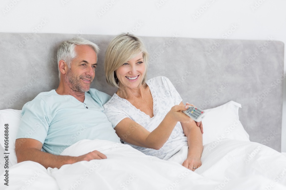 Happy couple watching tv in bed Happy couple watching tv in bed