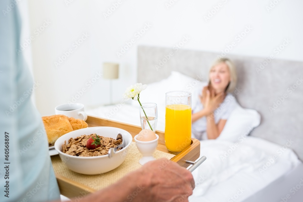 Woman sitting in bed with breakfast in foreground Woman sitting in bed with breakfast in foreground