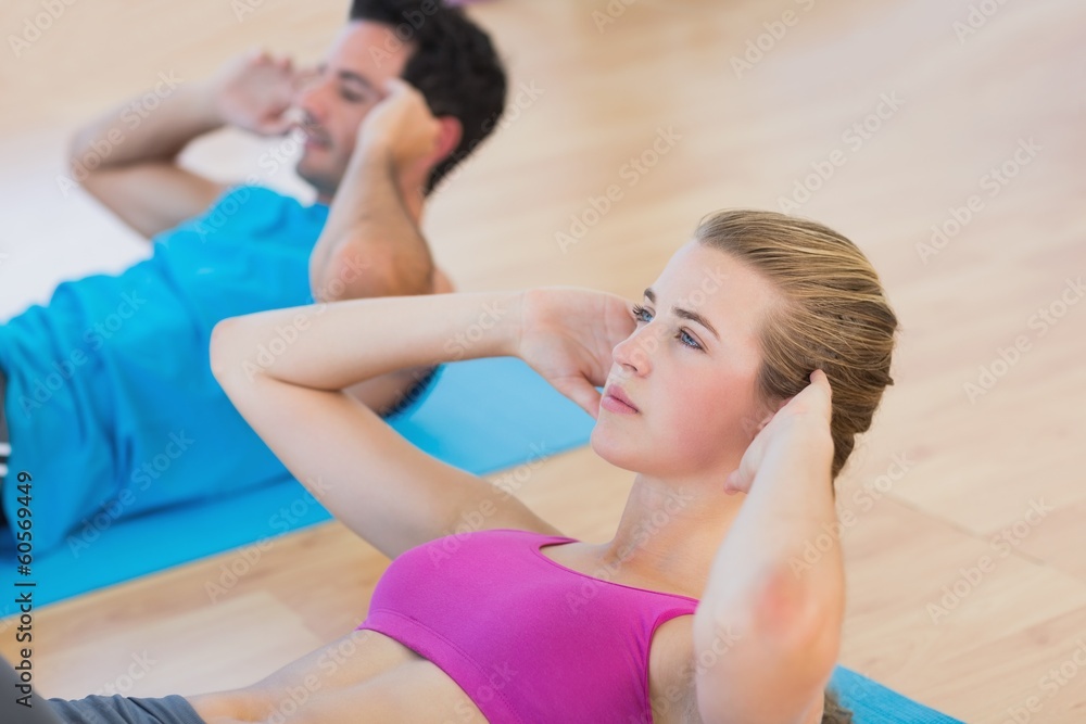 Fototapeta premium Side view of determined young couple doing sit ups