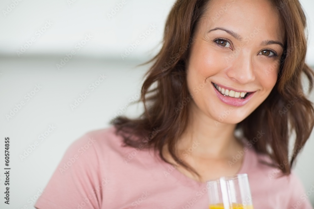Closeup of a smiling woman holding orange juice Closeup of a smiling woman holding orange juice