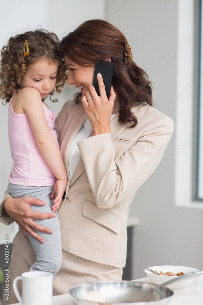 Well dressed mother carrying daughter while on call in kitchen Well dressed mother carrying daughter while on call in kitchen