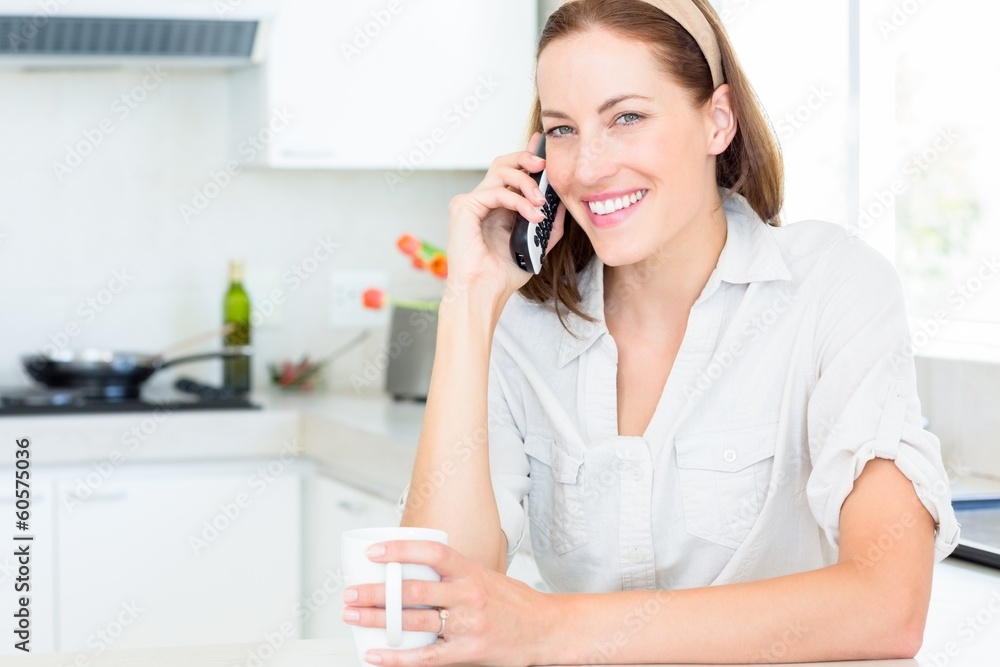 Smiling woman with coffee cup using mobile phone in kitchen Smiling woman with coffee cup using mobile phone in kitchen