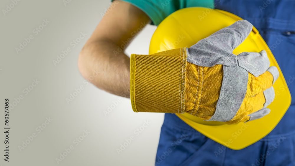 Workman wearing a glove holding a hardhat Workman wearing a glove holding a hardhat