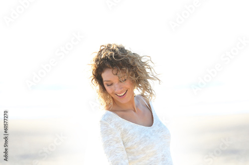 Beautiful smiling blond woman standing on a beach © goodluz