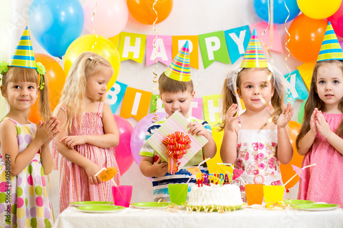 boy with gift and group of kids at birthday party