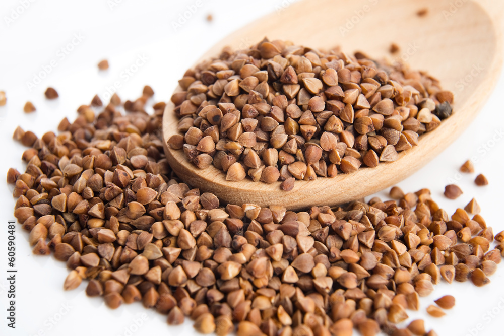 Buckwheat seeds on wooden spoon in closeup Buckwheat seeds on wooden spoon in closeup