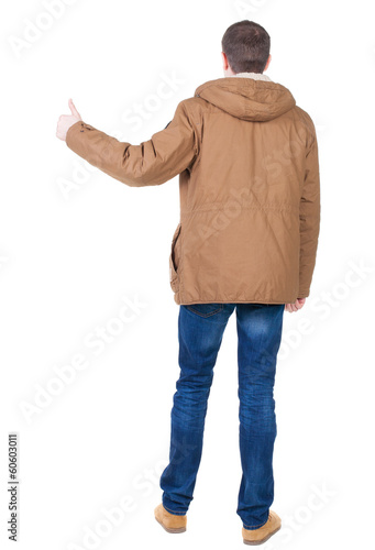 Back view of handsome man in winter jacket shows thumbs up.