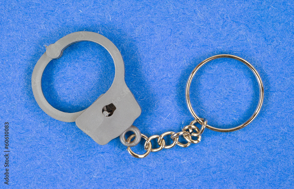 Toy handcuffs keychain on blue background Toy handcuffs keychain on blue background
