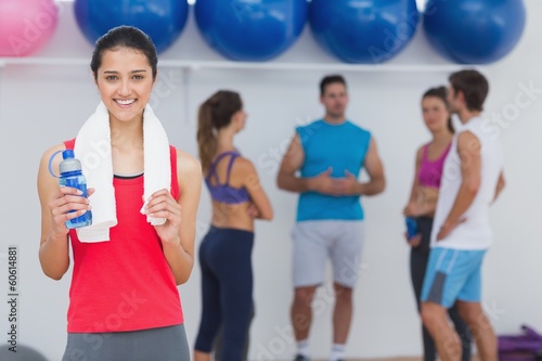 Female holding water bottle with fitness class in background