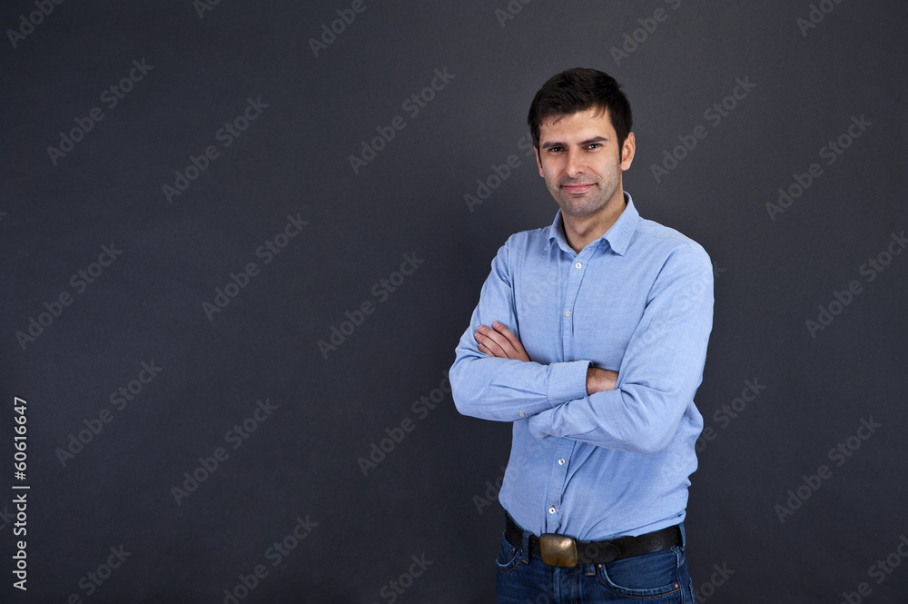 young handsome man smiling over gray background with crosed arms