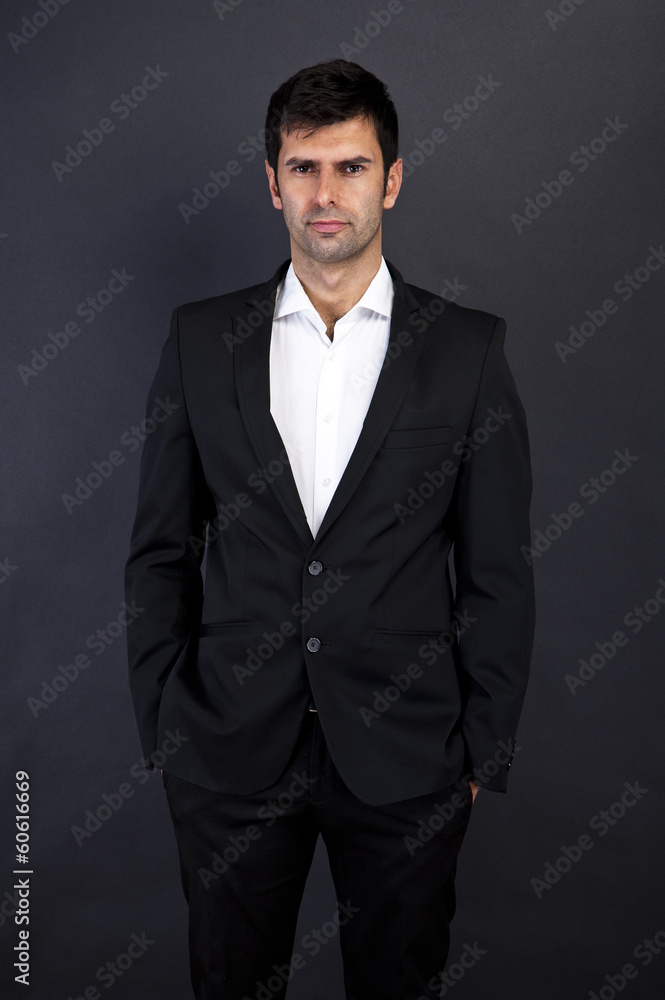 Young handsome man in black suit smiling on dark background Young handsome man in black suit smiling on dark background