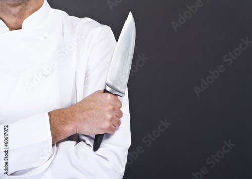 Portrait of a young cook man wearing uniform holding a knife ove