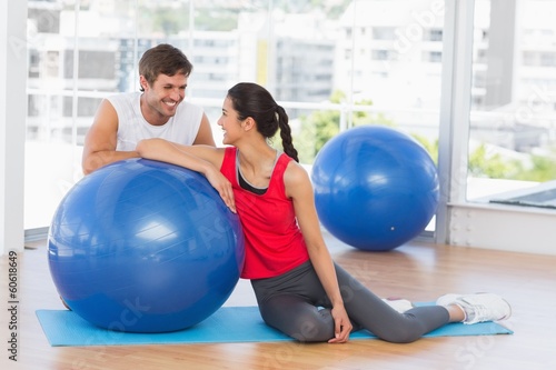 Smiling fit young couple with exercise ball at gym