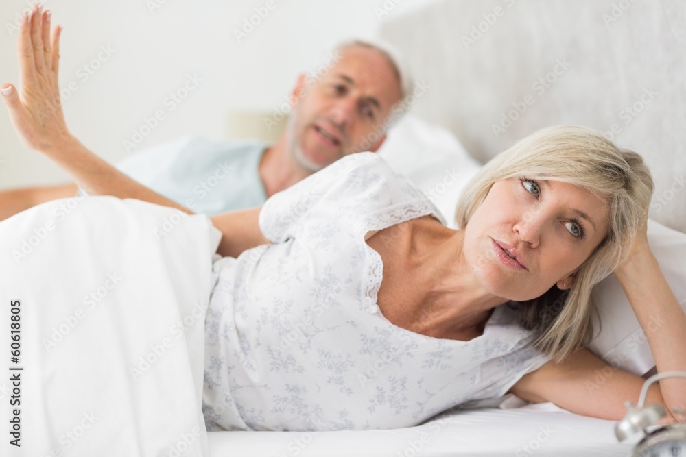 Woman ignoring mature man while lying in bed Woman ignoring mature man while lying in bed