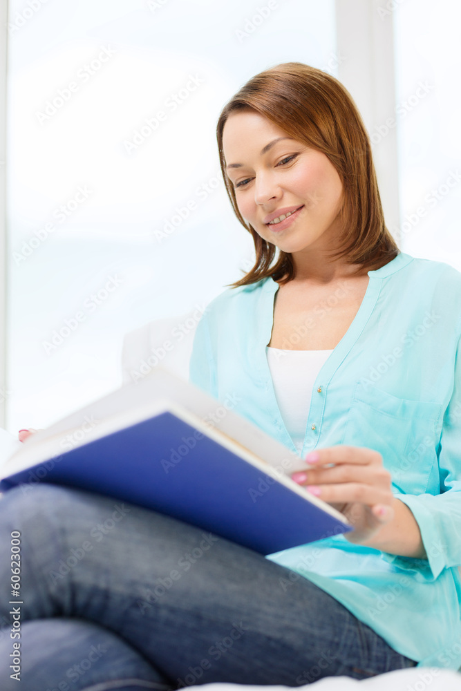 smiling woman reading book and sitting on couch smiling woman reading book and sitting on couch